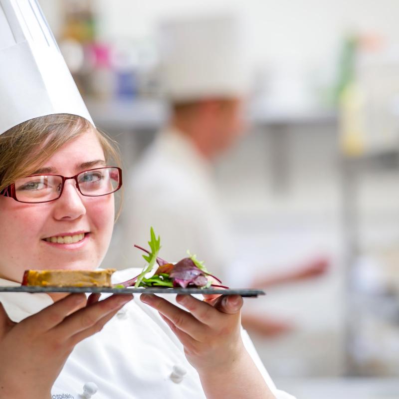 Female chef with a plate of food in a hotel kitchen